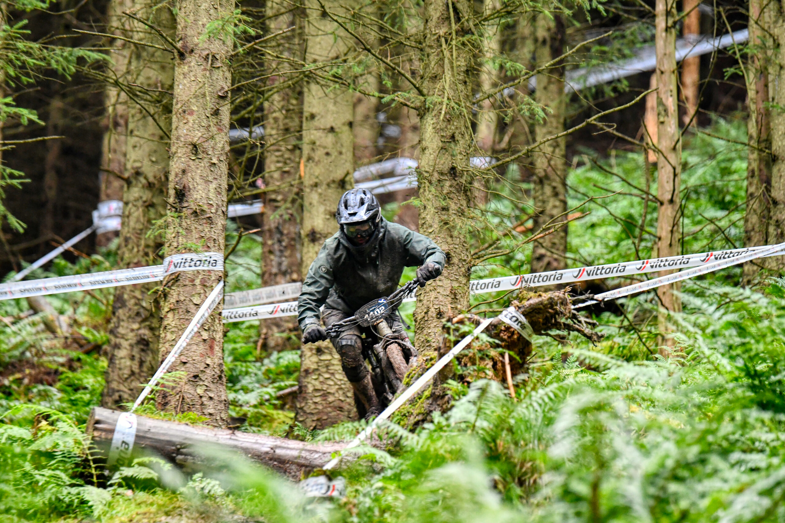 Roman navigating a technical forest section during an Enduro World Series race, fully focused and covered in mud, captured by Yari.