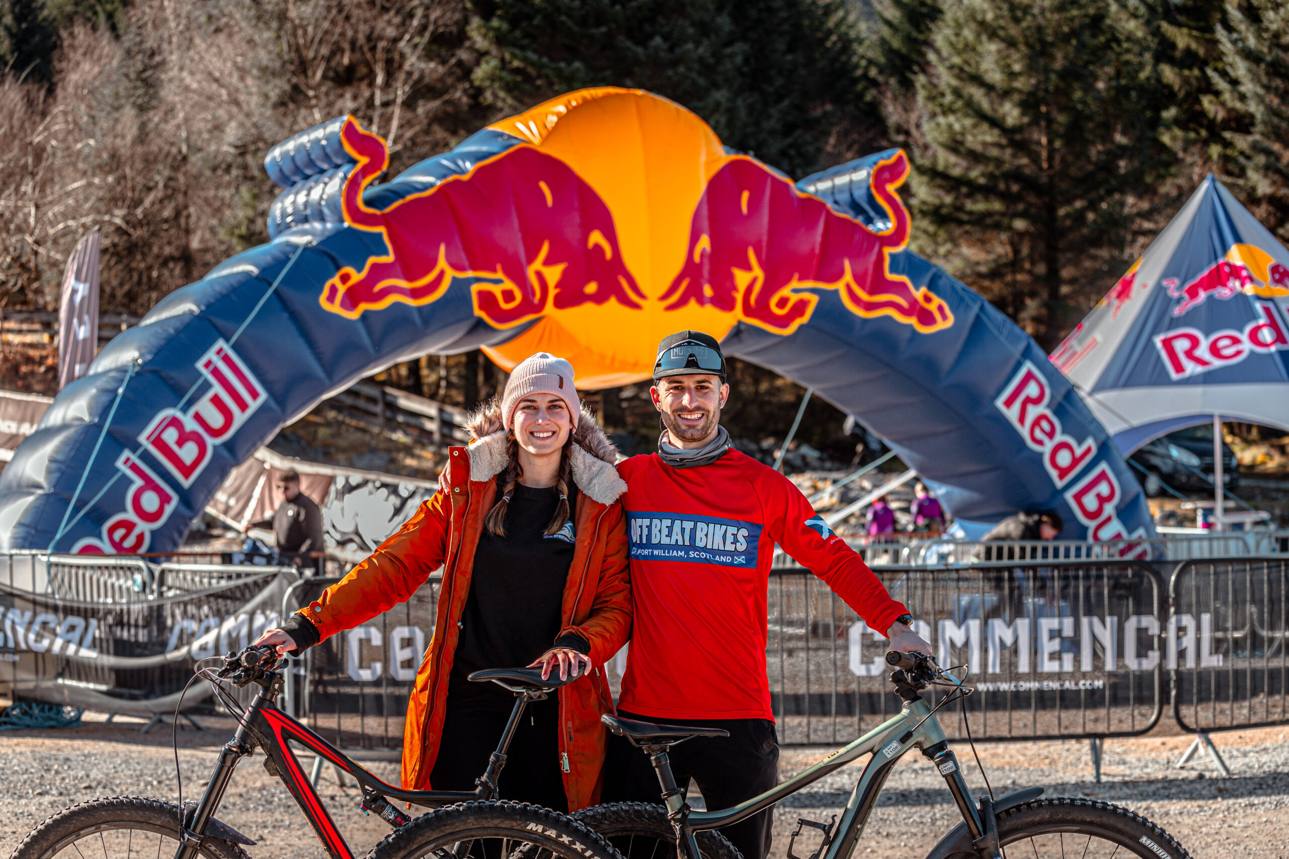 Roman and a fellow rider with their mountain bikes, standing in front of a Red Bull arch at the MacAvalanche event in Fort William.